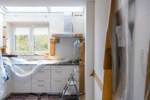 A kitchen under renovation with cabinets covered in plastic