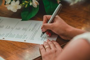 A person signing a printed document with a pen